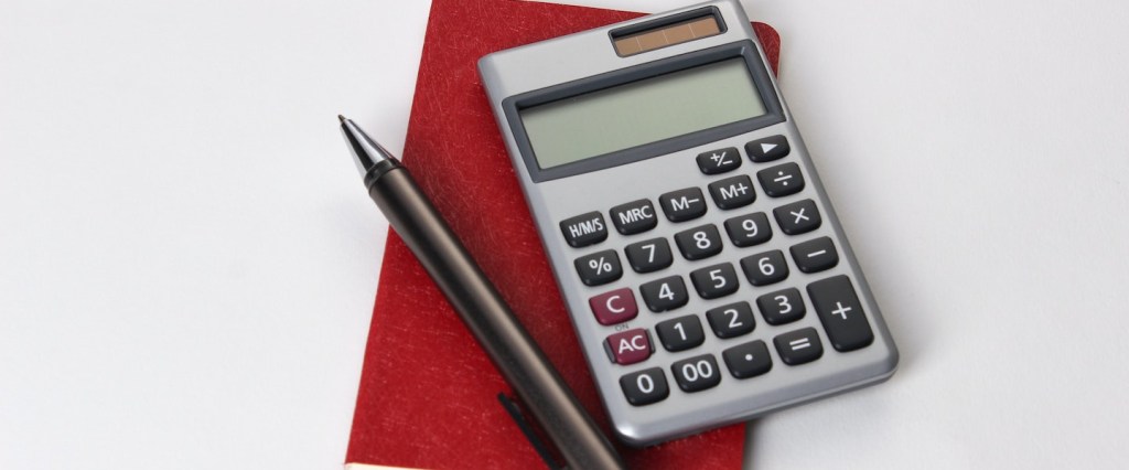 DAS Simples Nacional: uma calculadora cinza e uma caneta preta estão posicionadas sobre um caderno de capa vermelha