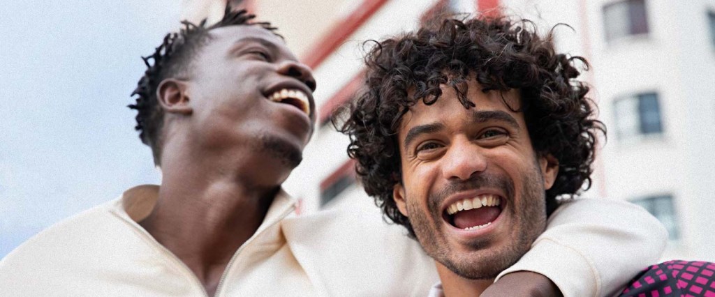 Dois homens se abraçando e sorrindo.