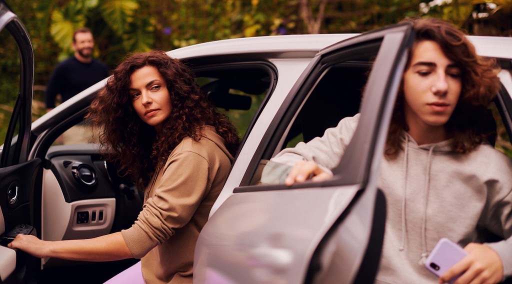 Na foto, uma mulher saindo do carro pela porta do motorista e um menino adolescente saindo da porta de trás do veículo.