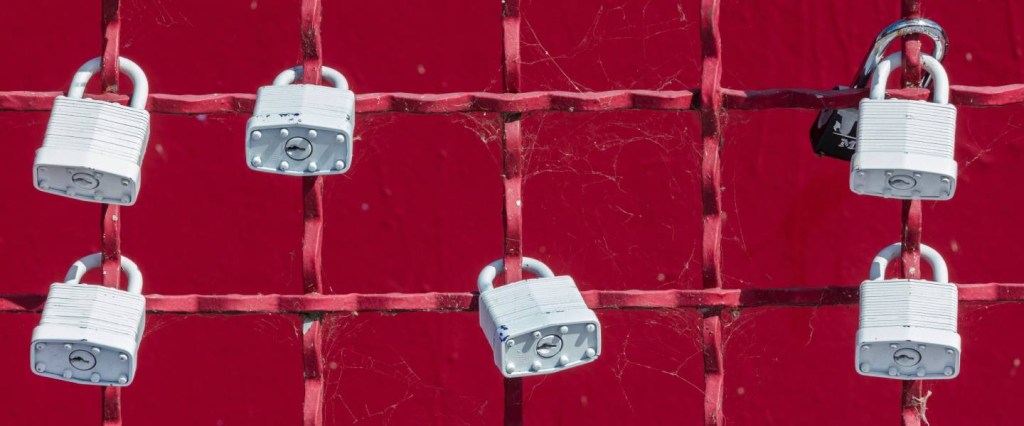 Ilustração mostra alguns cadeados brancos presos em uma grade vermelha.