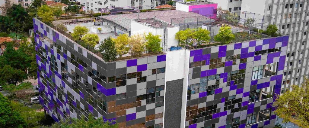 O Nubank é brasileiro? Na imagem aérea aparece o escritório do Nubank, em São Paulo, um prédio cúbico e com paredes com quadrados roxos envolto em árvores.