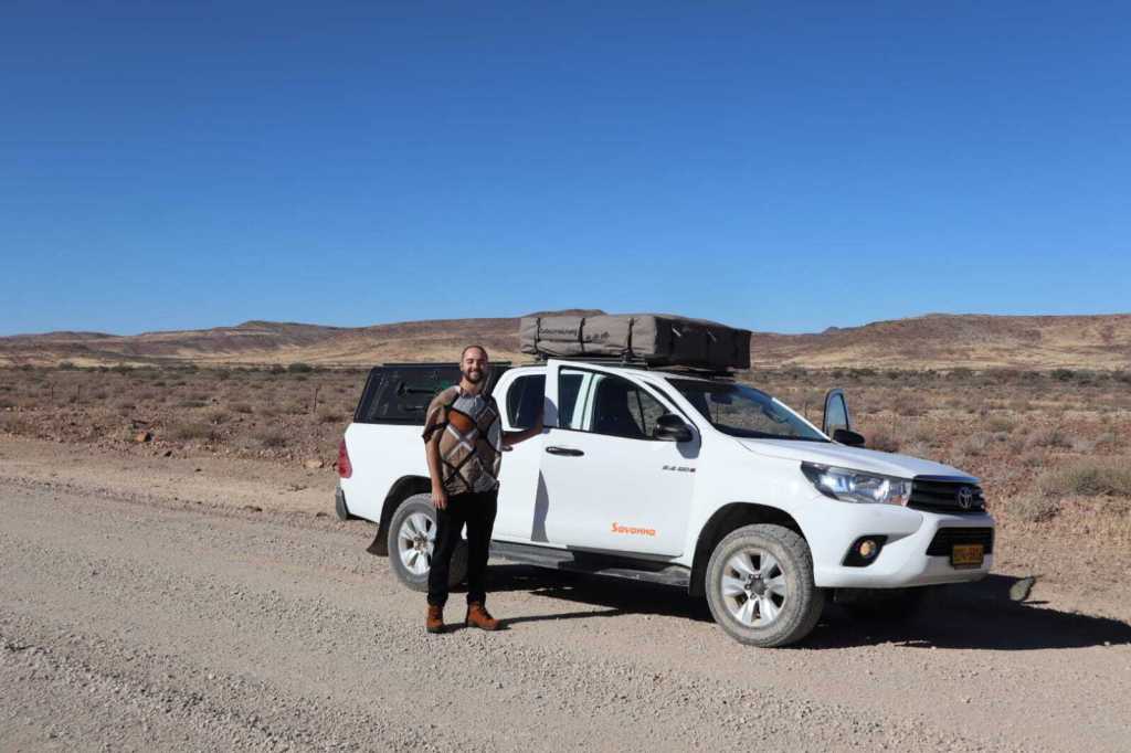 Na foto do arquivo pessoal do Pedro, ele em frente ao seu carro no deserto da Namíbia.
