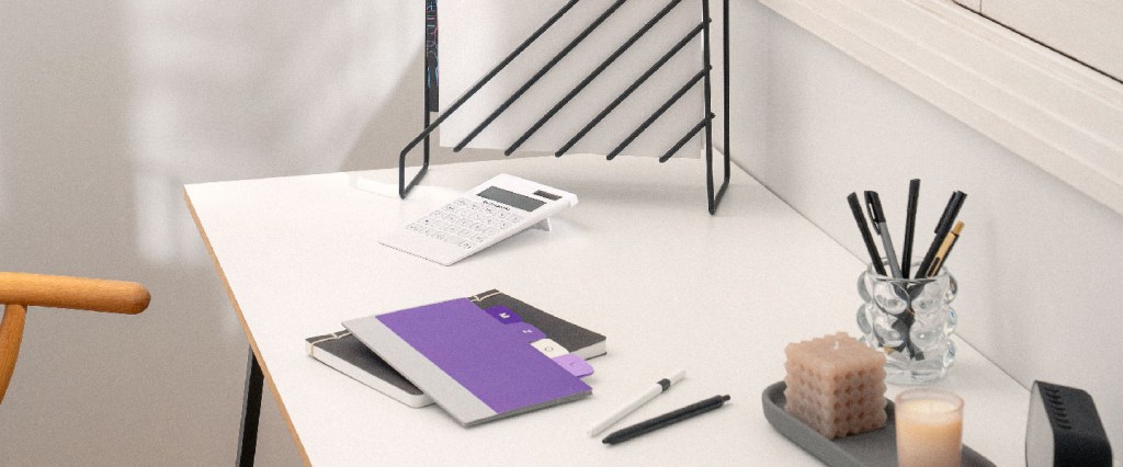 Cobranças indevidas: mesa com caderno, calculadora e lápis remetendo a gestão financeira