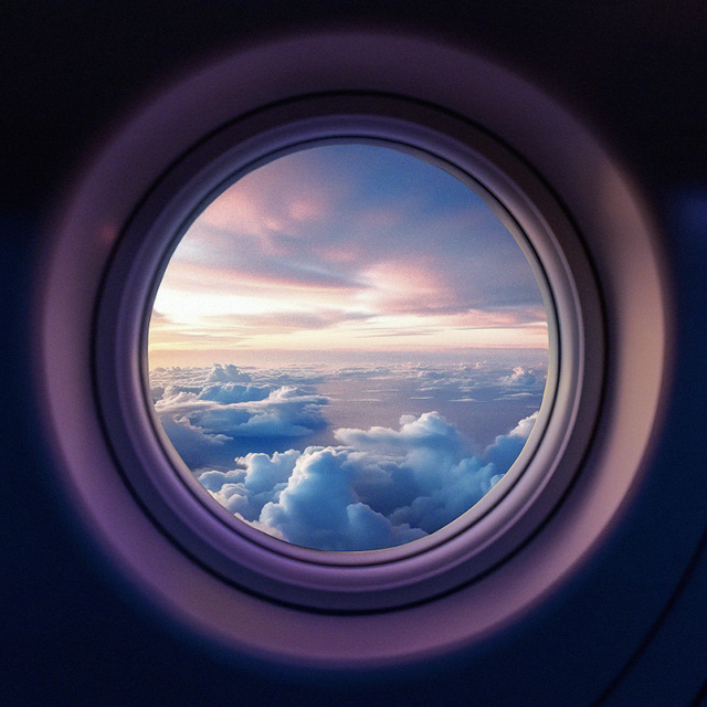 Foto da janela redonda de um avião, aparecendo as nuvens do lado de fora.