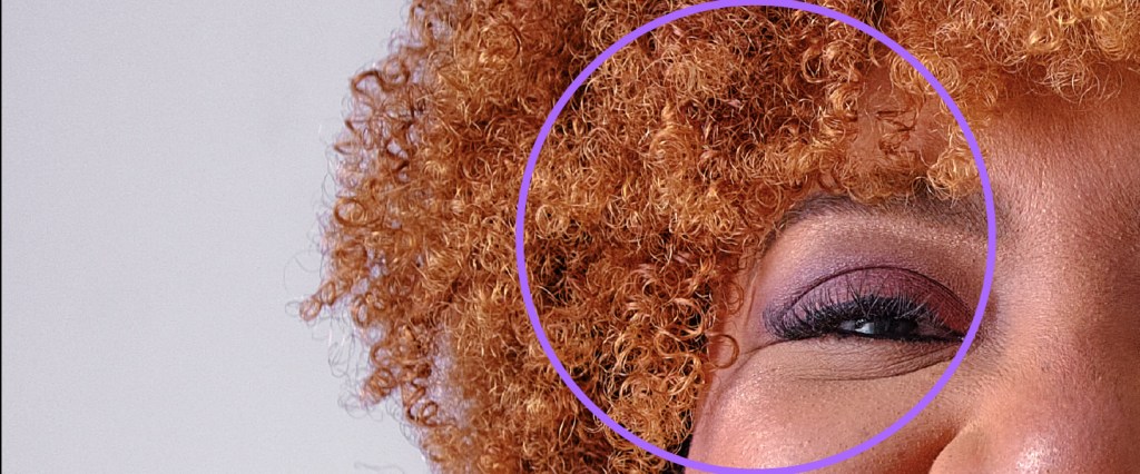 ESG no Nubank: imagem dos olhos de uma mulher negra, de cabelos cacheados e ruivos. No centro da imagem, há um círculo roxo.