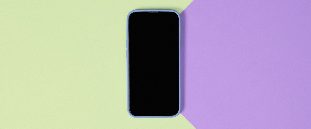 Celular seguro: imagem de um celular desligado sobre uma superfície verde e roxa.