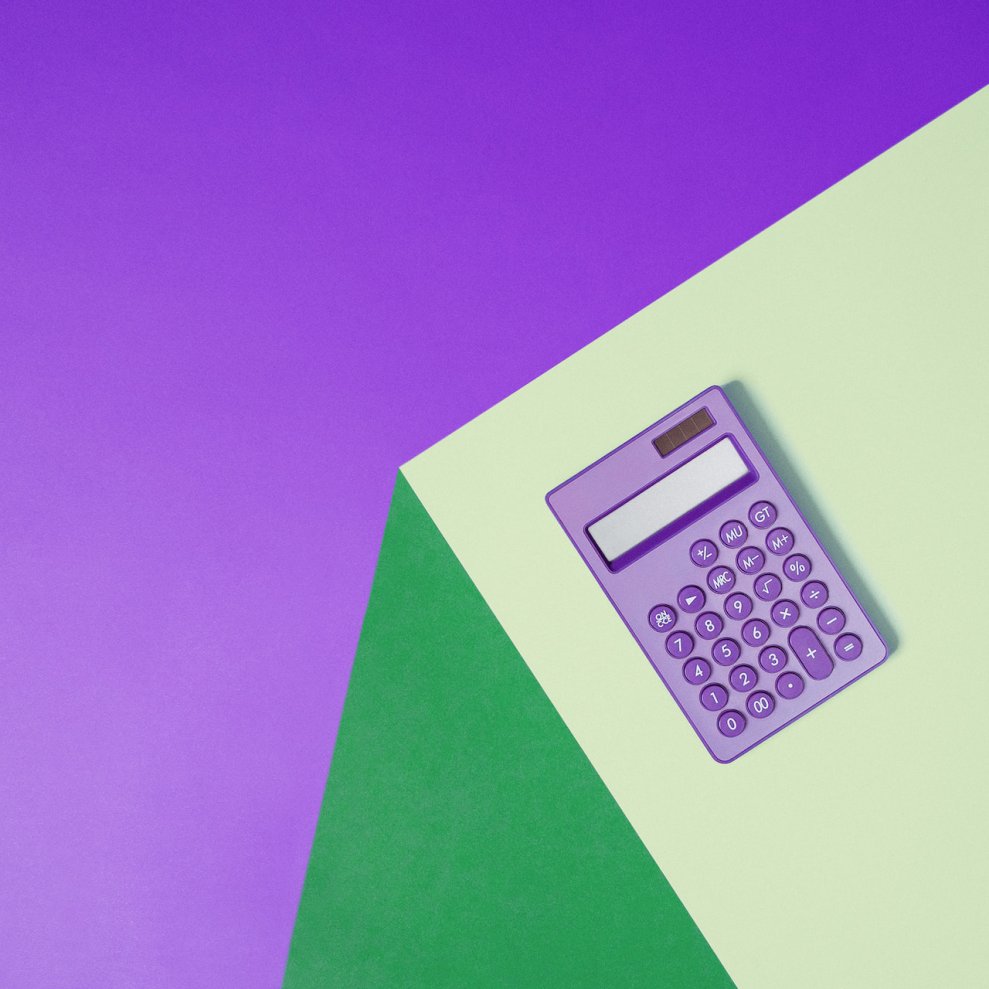 Juros rotativos: Imagem de uma calculadora roxa sobre uma mesa verde. O fundo da imagem também é roxo.