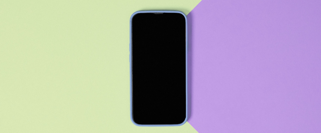 Como trabalhar com inteligência artificial: imagem de um celular desligado sobre uma superfície verde e roxa.