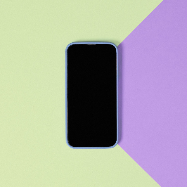 Como trabalhar com inteligência artificial: imagem de um celular desligado sobre uma superfície verde e roxa.