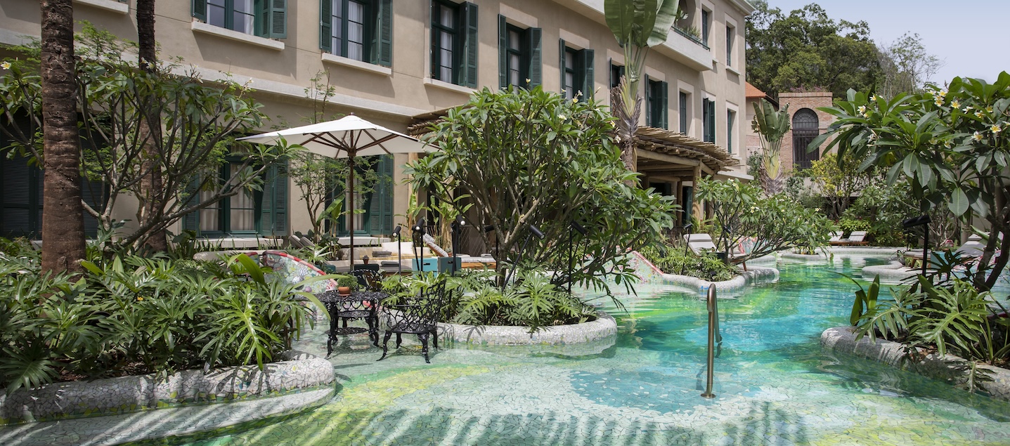 Área externa do Hotel Rosewood São Paulo. Há uma piscina rodeada por grandes plantas.